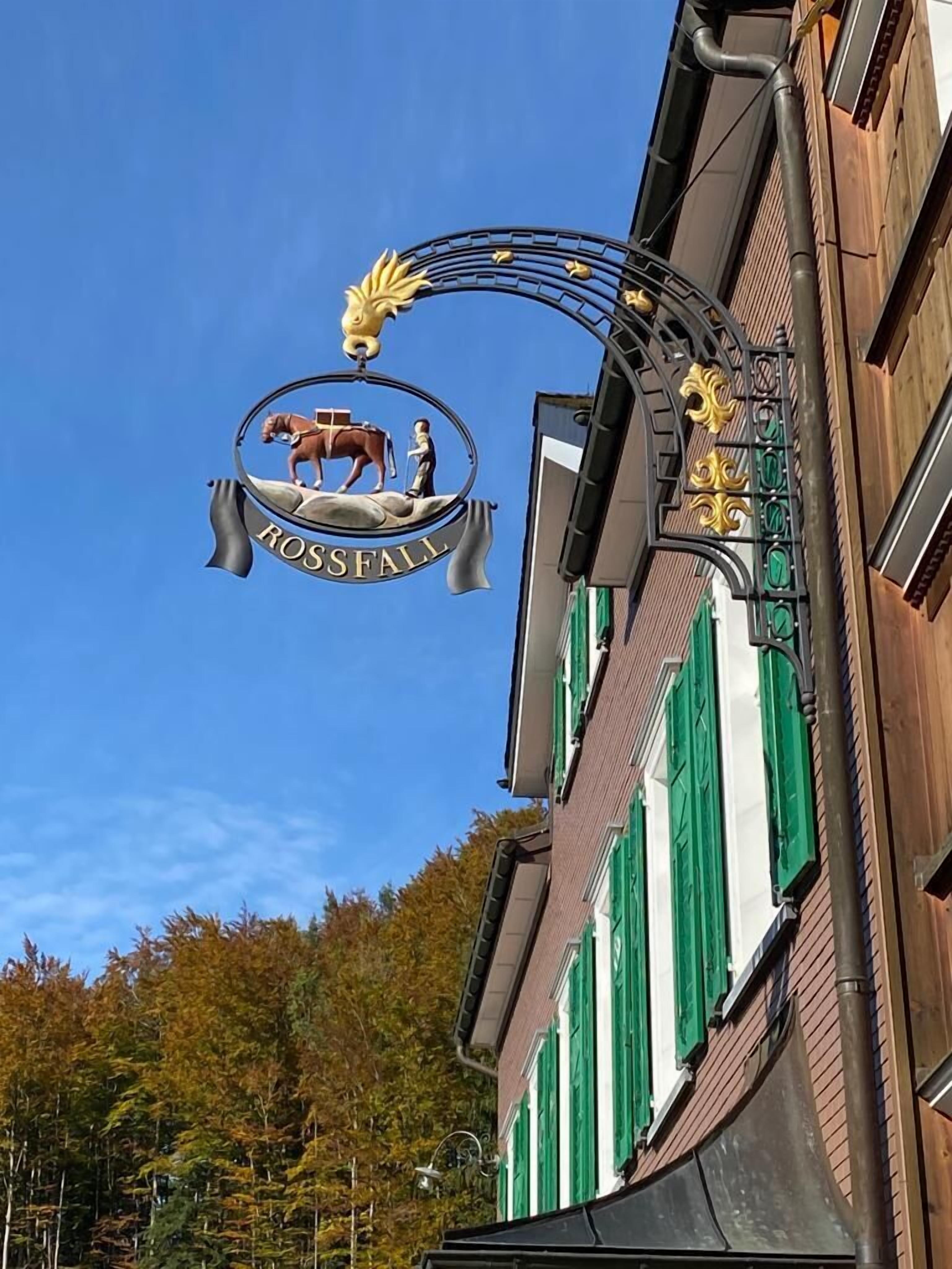 Un bâtiment sur lequel est apposée une enseigne indiquant « ROSSFALL », et qui présente un emblème représentant un cheval et un cavalier.
