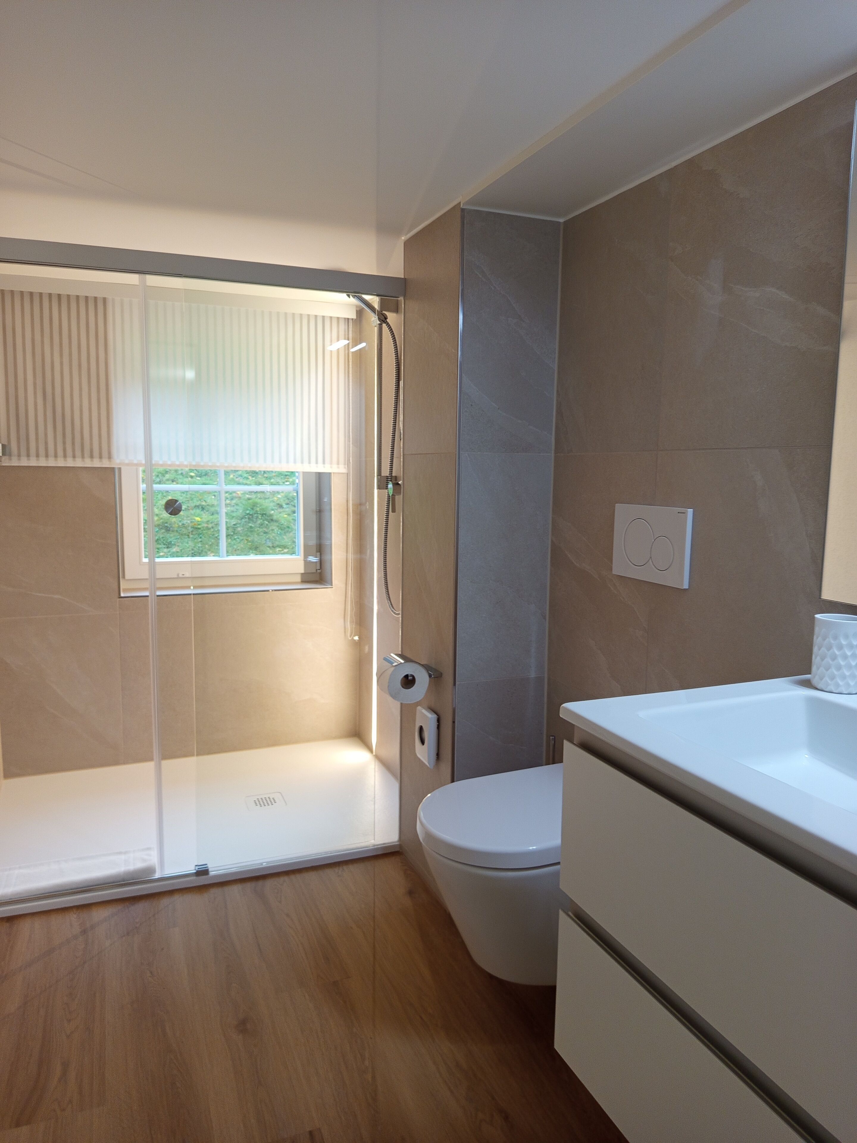 Un baño moderno con ducha, inodoro y lavamanos.