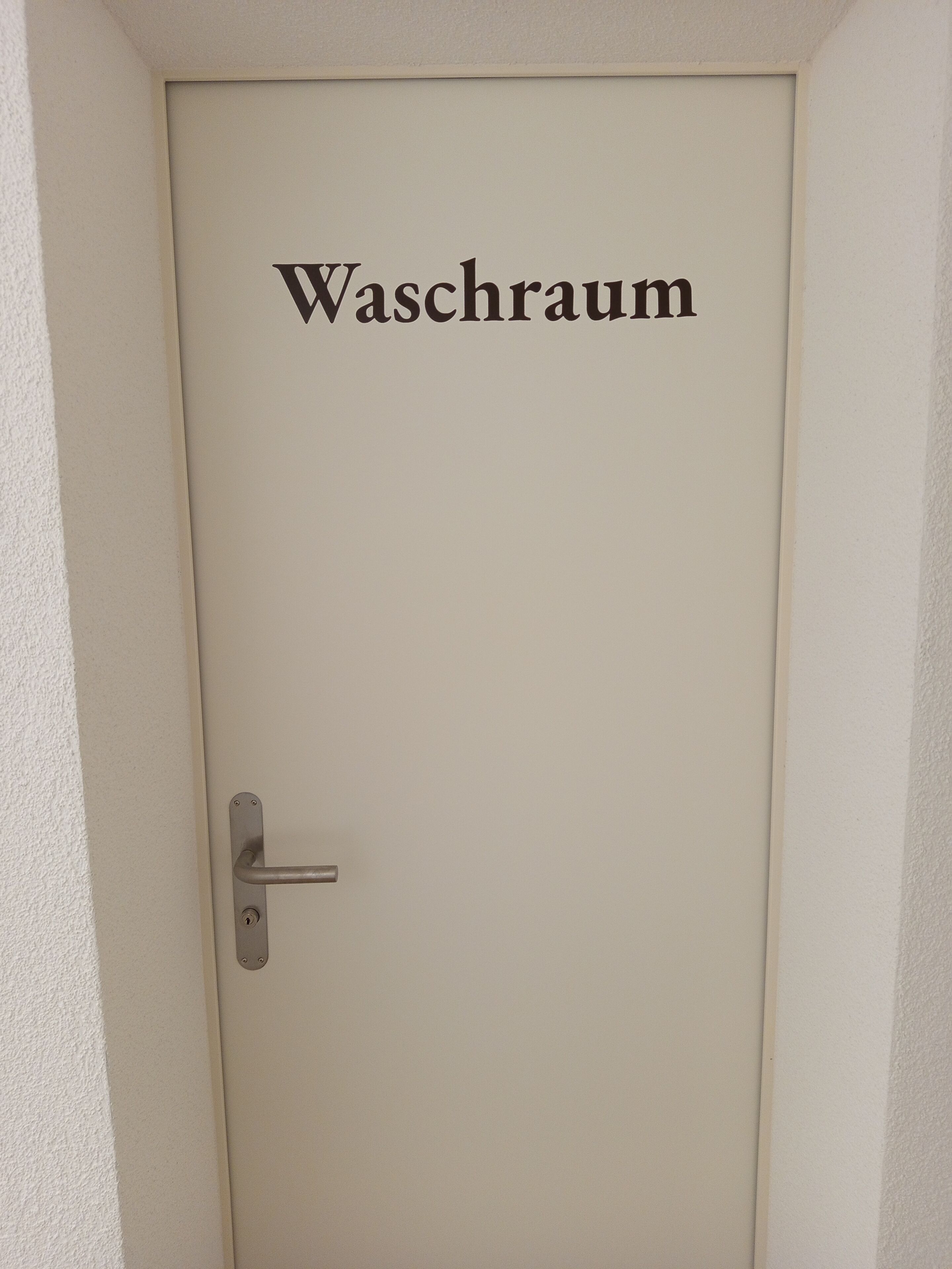 A door labeled "Waschräum" with a simple metal handle and a keyhole.