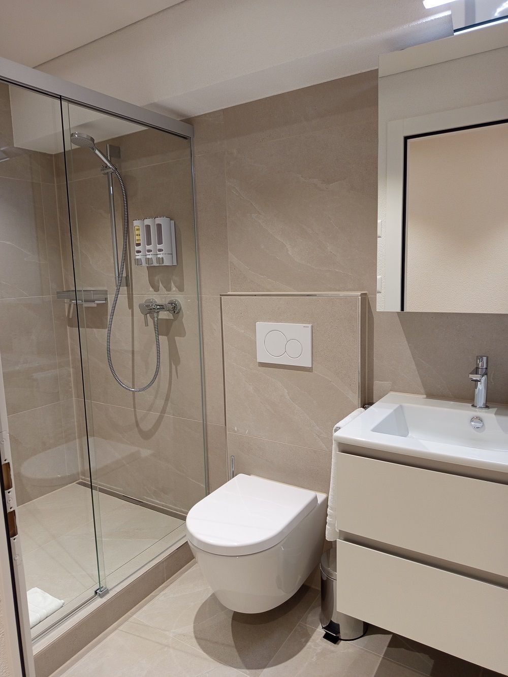 A modern bathroom with a glass-enclosed shower, a toilet, and a vanity with a sink.