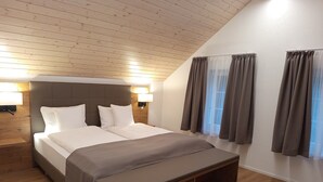 A modern bedroom with a large bed, wooden headboard, bedside lamps, and a bench at the foot of the bed. - Gästehaus Rossfall 424 - Self-Check-in (Urnaesch)