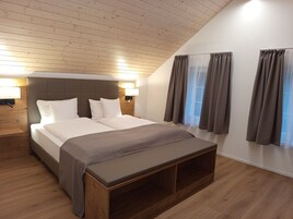 Un dormitorio moderno con una cama grande, cabecera de madera, lámparas de noche y un banco al pie de la cama.