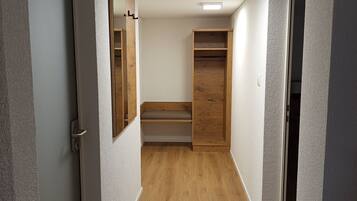 A hallway with wooden flooring, white walls, and a ceiling light.