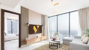 Ein modernes Wohnzimmer mit großem Fenster, einer Couch, einem Couchtisch und einem an der Wand befestigten Fernseher.