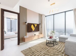 A modern living room with a large window, a sofa, a coffee table, and a TV mounted on the wall.