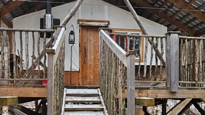 A wooden cabin with a staircase leading to a door, surrounded by snow and trees. - Unique cabin perched high with white pine trees (Mansfield-et-Pontefract)