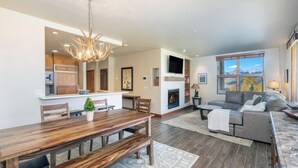 A spacious living room with a fireplace, a large wooden dining table, and a comfortable sofa.