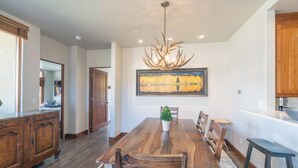 A dining room with a large wooden table, chairs, and a chandelier.