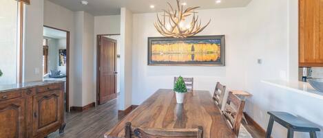 A dining room with a large wooden table, chairs, and a chandelier.