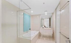 Un bagno moderno con cabina doccia in vetro, una vasca da bagno freestanding e un mobile vanitario con specchio.