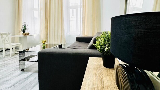 A modern living room with a sofa, a coffee table, a TV, and a potted plant.