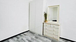 A room with a white wardrobe, a mirror, and a plant on a dresser.