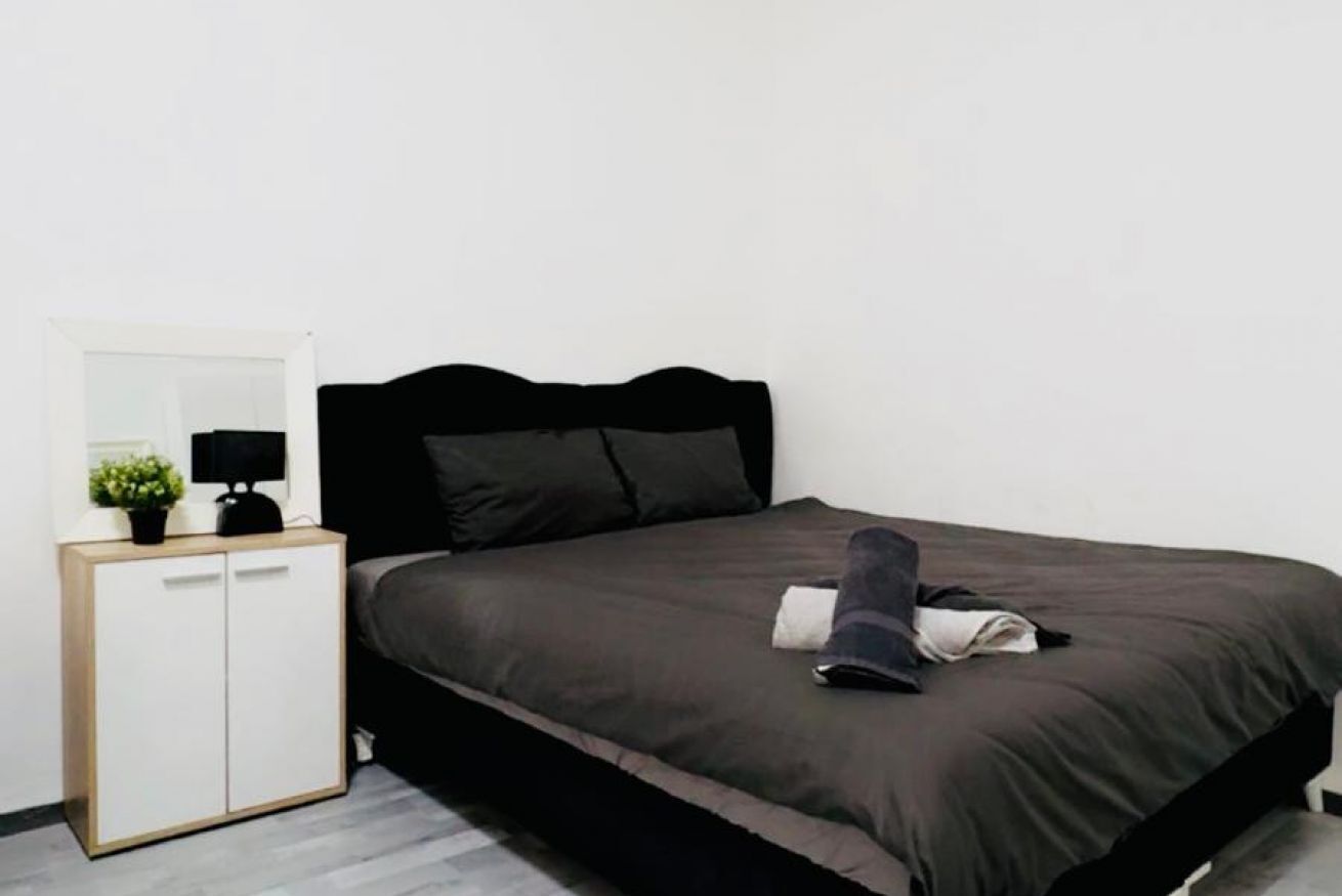 Ein Schlafzimmer mit Bett, Nachttisch, Spiegel und Kleiderschrank.