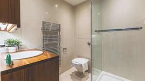 Ein modernes Badezimmer mit einem Holzwaschtisch, einer Duschkabine aus Glas und einer weißen Toilette.