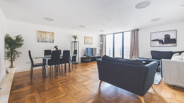 Ein modernes Wohnzimmer mit Essbereich, großen Fenstern und Kunstwerken an den Wänden.