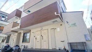A two-story residential building with a tiled facade, a balcony, and a visible entrance.