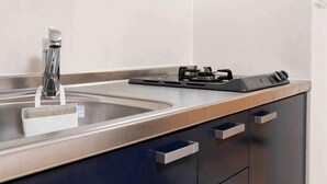 A kitchen with a stainless steel sink, a modern faucet, and a black electric stove.