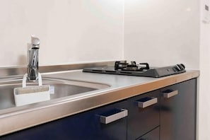 A kitchen with a stainless steel sink, a modern faucet, and a black electric stove.