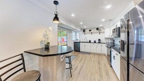 A modern kitchen with a central island, stainless steel appliances, and a pendant light. - Big backyard hangout, firepit, large primary suite (Sarasota)