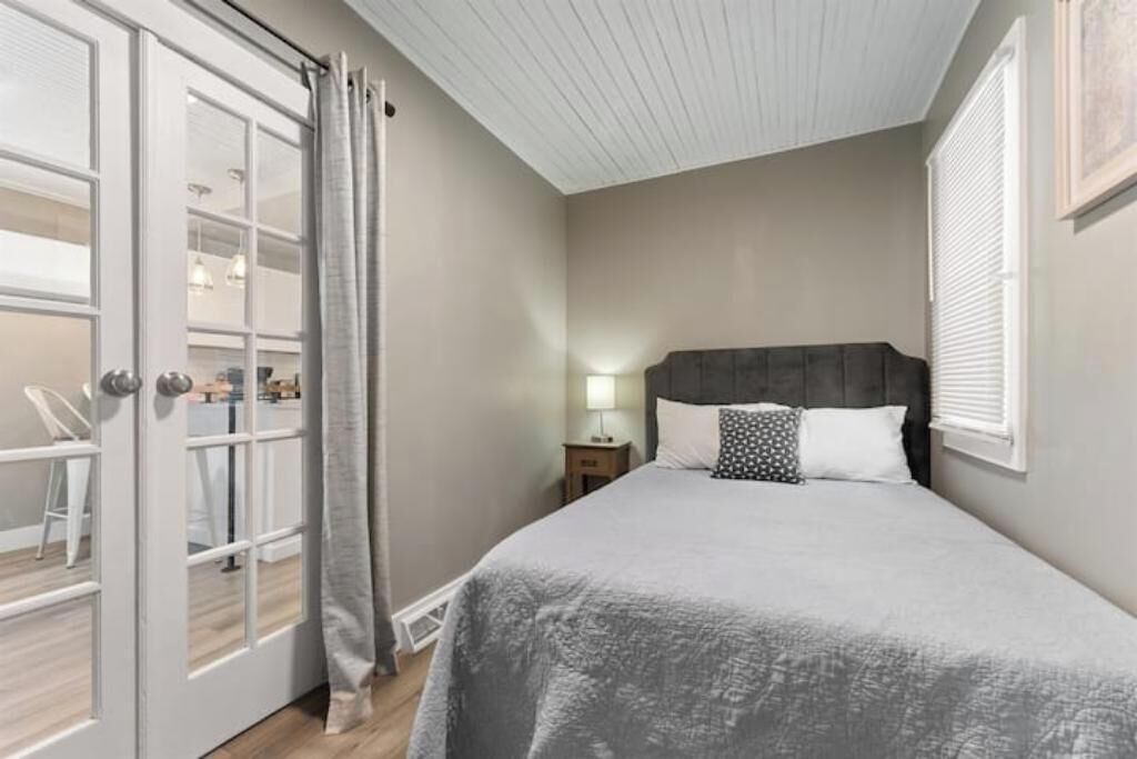 A bedroom with a bed, a nightstand, a lamp, and a window with blinds.