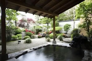 A tranquil garden with a pond, stone pathways, and various shrubs and trees. - City Yugawa Room D (Hakodate)
