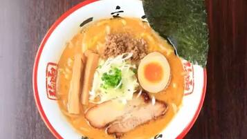 A bowl of ramen with various toppings including noodles, a boiled egg, and vegetables.