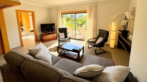 Ein Wohnzimmer mit Sofa, Couchtisch, Fernseher und Sesseln.