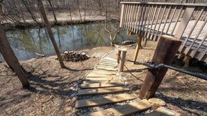 A wooden staircase leading to a deck over a pond, surrounded by trees. - Historic Canal Retreat in Downtown Canal Fulton (Canal Fulton)