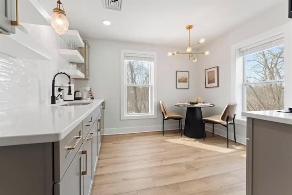 Een moderne keuken met witte kasten, een centraal eiland en een eethoek met twee stoelen.