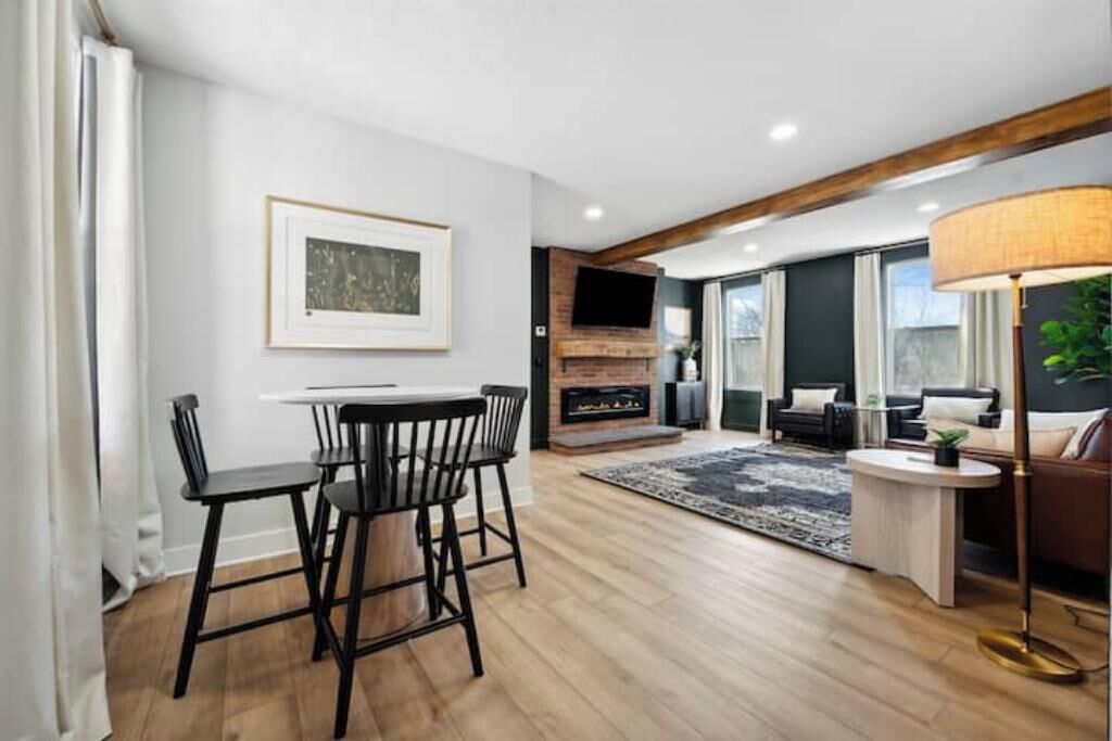 Uma sala de estar moderna com lareira, uma área de jantar com mesa e cadeiras, e um conjunto de sofás.