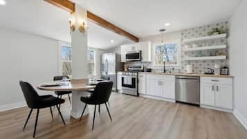 Een moderne keuken met witte kasten, een houten eettafel en zwarte stoelen.