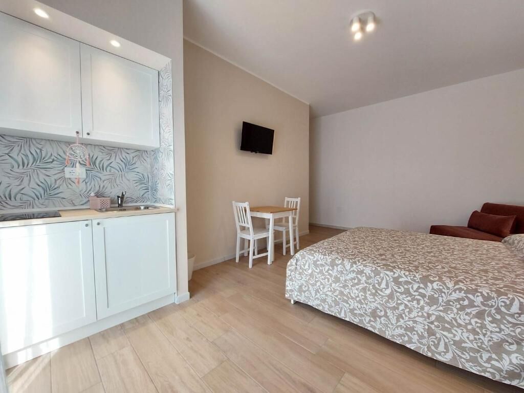 Een kleine kamer met een bed, een tafeltje en een kitchenette.