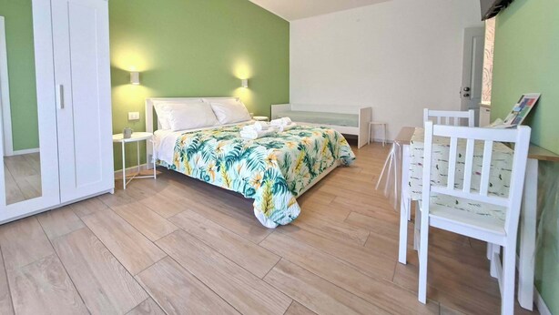 A bedroom with a bed, a chair, a wardrobe, and a TV mounted on the wall. - Ricomincio da Polignano (Polignano a Mare)