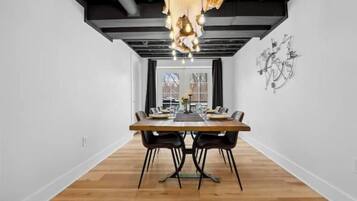 A modern dining area with a wooden table, black chairs, and a unique chandelier.