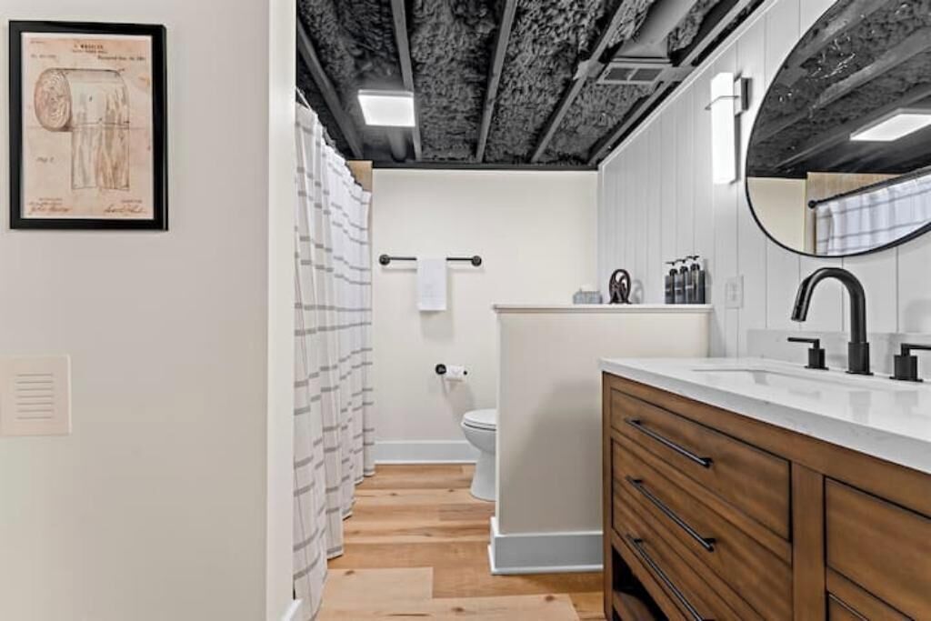 A modern bathroom with a wooden vanity, a large mirror, and a toilet.