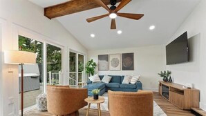 Un amplio salón con ventilador de techo, un conjunto de sofás azules y un mueble de madera.