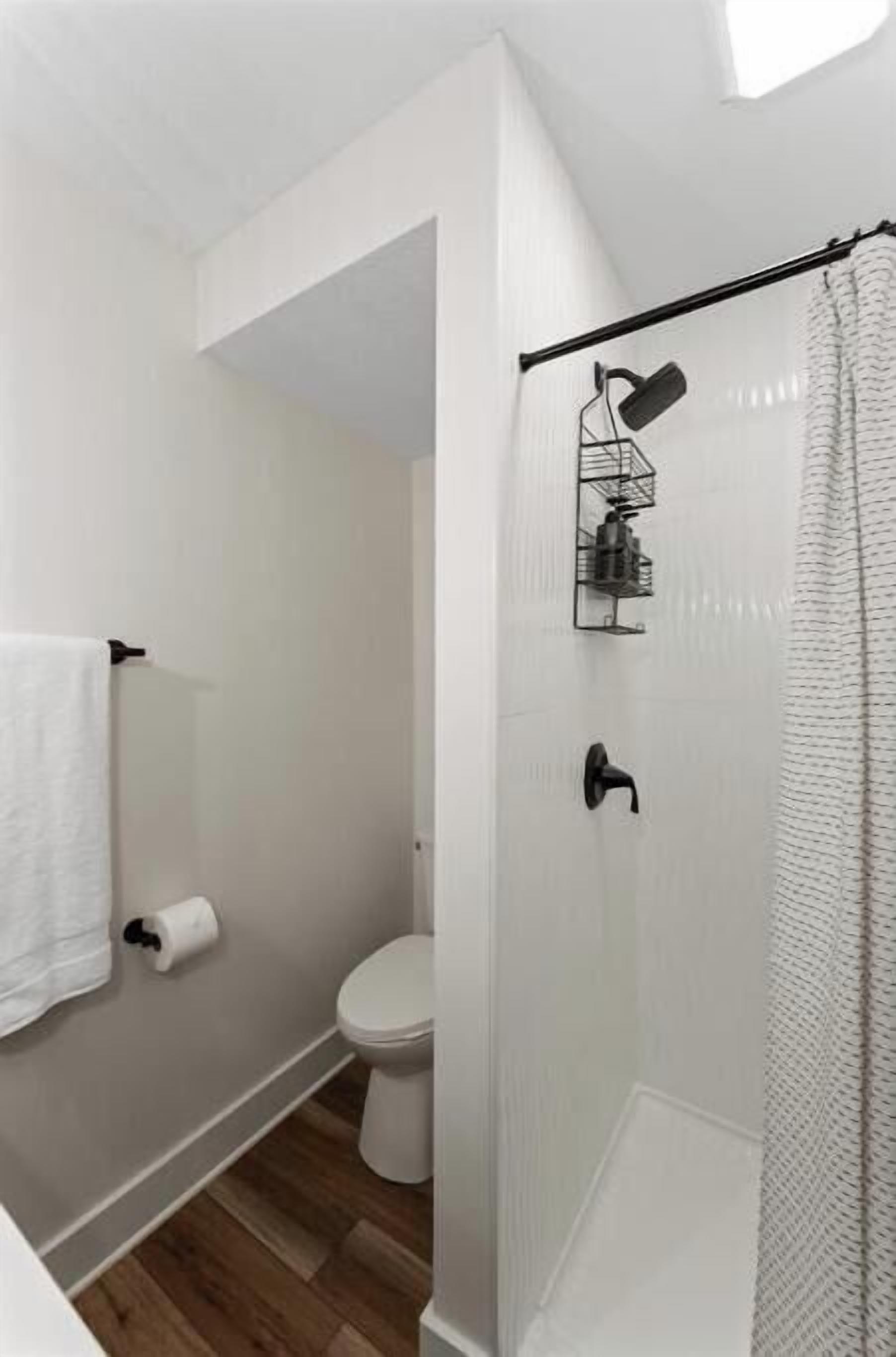 A modern bathroom with a shower, toilet, and a towel rack.