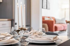 Uma mesa de jantar posta com pratos, copos e talheres, com velas e um arranjo decorativo.