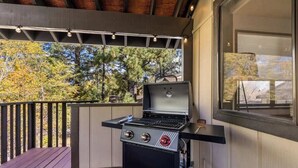 Una griglia da barbecue su un pontile di legno con vista sugli alberi.