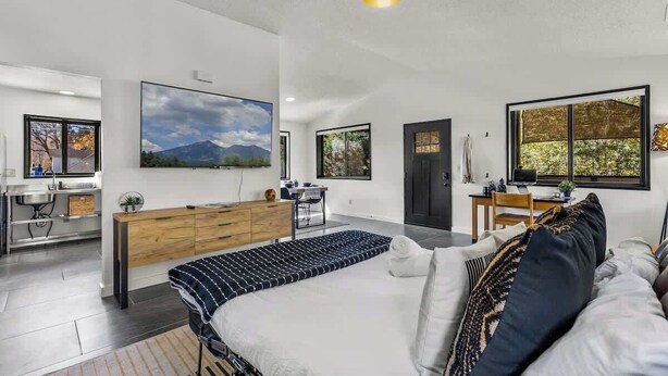 Camera da letto moderna con un letto grande, una scrivania e vista all'esterno da una finestra.