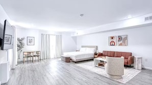 Une chambre d’hôtel moderne équipée d’un lit, d’un canapé, d’une table à manger et d’un téléviseur.