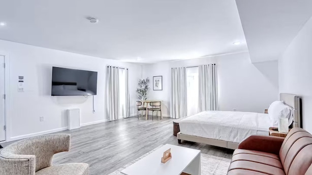 Une chambre d’hôtel moderne dotée d’un grand lit, d’un canapé, d’une télévision et d’un coin repas.