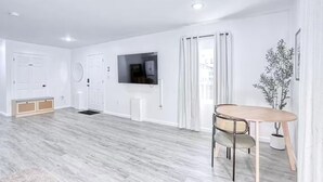 Un salon moderne avec un téléviseur à écran plat, une table à manger avec des chaises et une plante en pot.