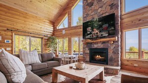 A cozy cabin interior with a stone fireplace, wooden ceiling, and large windows. - NorthLong Lake/Hot Tub, Sandy Beach (Brainerd)