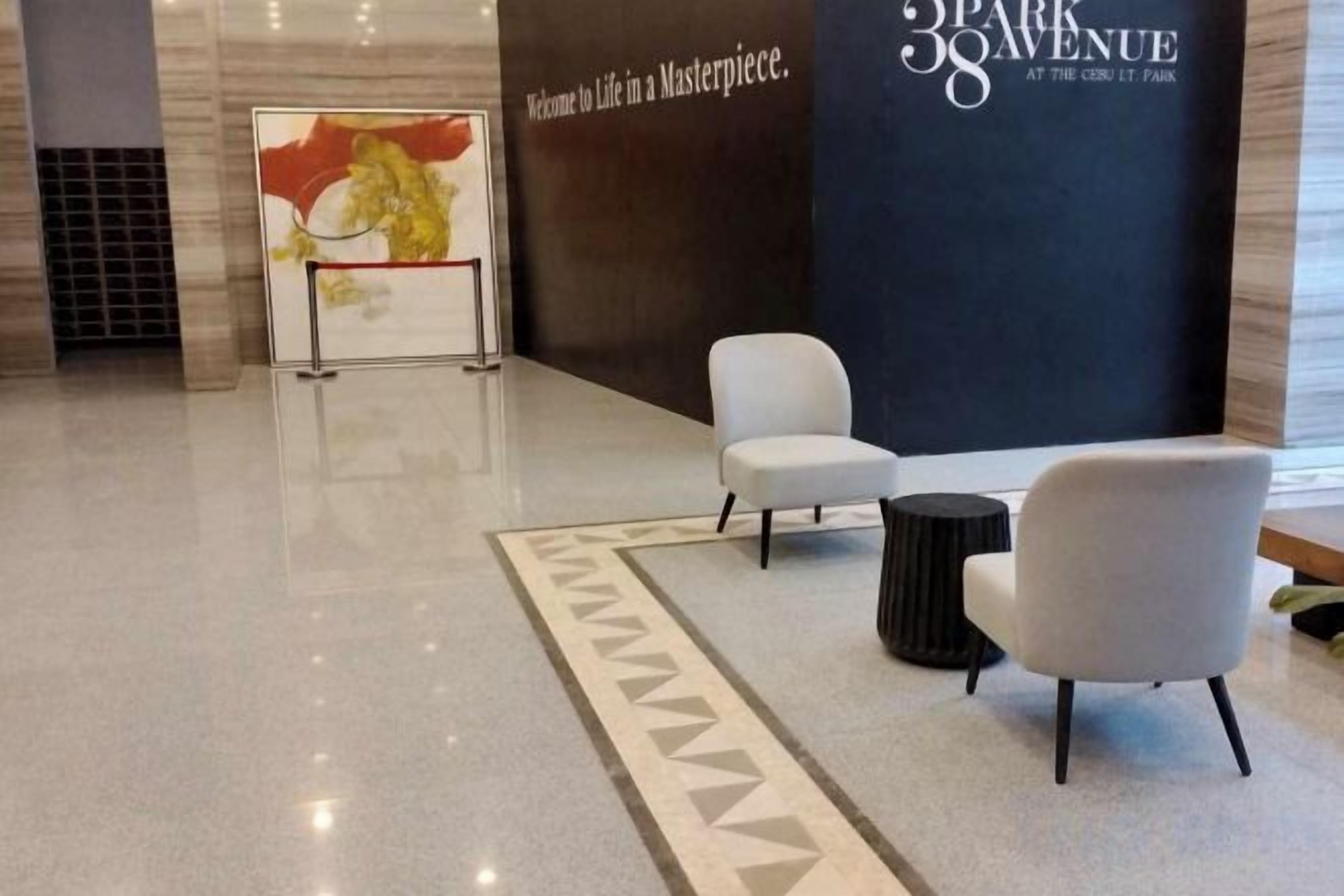 Un vestíbulo con mostrador de recepción, dos sillones blancos, una mesa redonda negra y una alfombra estampada.