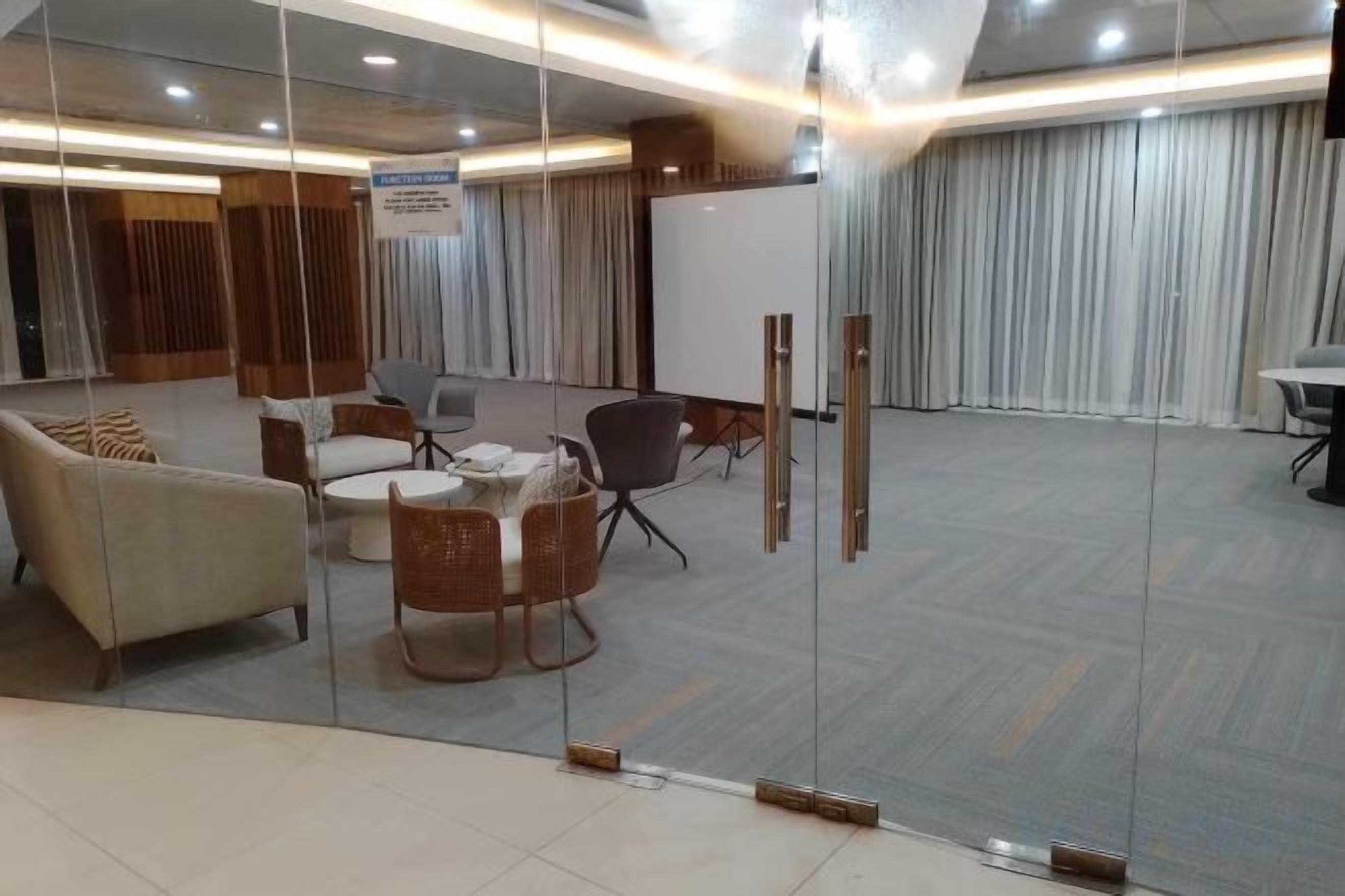 A conference room with glass walls, a whiteboard, and a seating arrangement including a sofa and chairs.