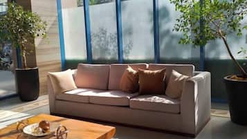 A modern living room with a beige sofa, a wooden coffee table, and two potted plants.