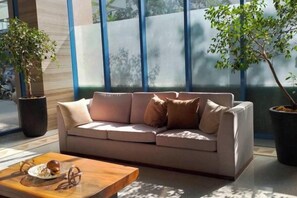 A modern living room with a beige sofa, a wooden coffee table, and two potted plants. - The City Escape (Cebu City)