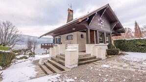 Ein Chalet mit steilem Dach, Schornstein und einer Steintreppe, die zum Eingang führt.