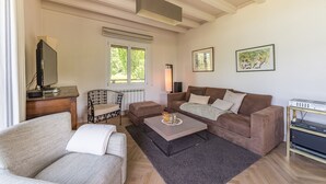 Ein Wohnzimmer mit Sofa, Sessel, Couchtisch und Fernseher auf einem Holzschrank.